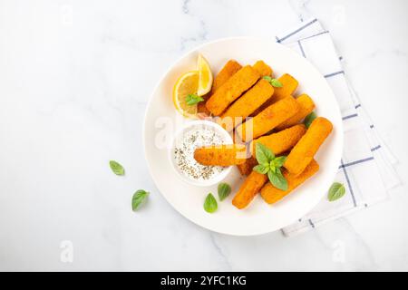 Fish and chips .Close up of crispy breaded deep fried fish fingers with breadcrumbs served with remoulade sauce and lemon Stock Photo