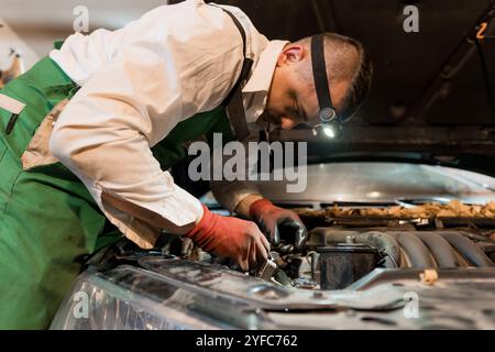 Mechanic Performing Maintenance on a Car Engine with Focus and Precision. Stock Photo