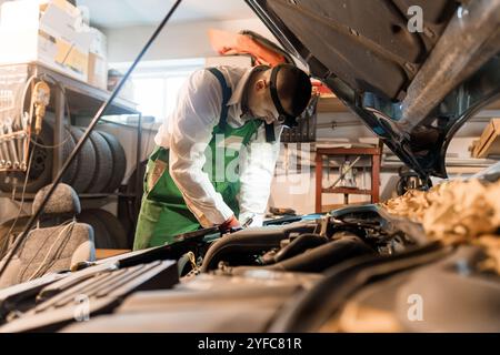 Mechanic Working on a Car Engine in a Workshop. Stock Photo