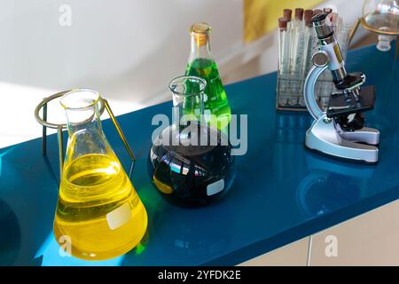 A close-up view of a laboratory setup featuring colorful chemical solutions in various glassware, including Erlenmeyer flasks and round-bottom flasks Stock Photo