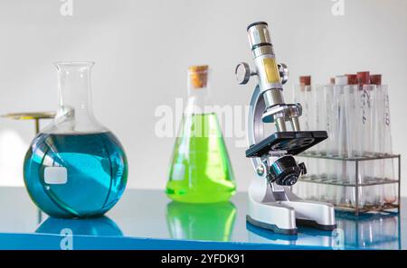 A close-up view of a laboratory setup featuring colorful chemical solutions in various glassware, including Erlenmeyer flasks and round-bottom flasks Stock Photo
