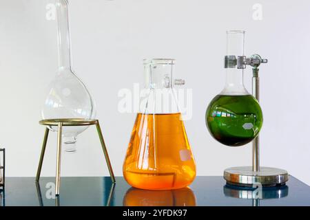 A close-up view of a laboratory setup featuring colorful chemical solutions in various glassware, including Erlenmeyer flasks and round-bottom flasks Stock Photo