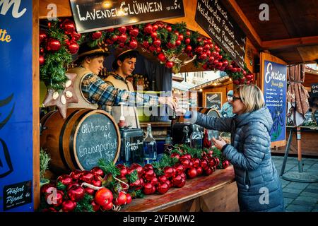 Woman buys hot mulled wine from wooden kiosk at annual Christmas market in Vienna, Austria. Stock Photo