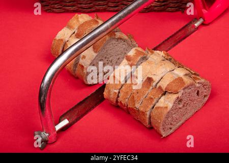 Creative Concept of Sliced Bread with Hacksaw on Red Background - Unique Image for Art, Abstract, and Food-Related Visuals Stock Photo