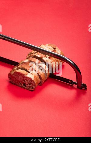 Creative Concept of Sliced Bread with Hacksaw on Red Background - Unique Image for Art, Abstract, and Food-Related Visuals Stock Photo
