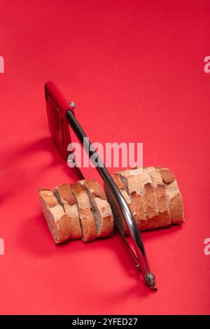 Creative Concept of Sliced Bread with Hacksaw on Red Background - Unique Image for Art, Abstract, and Food-Related Visuals Stock Photo