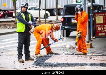 Construction workers in New York City repair a road, with one using a jackhammer, another breaking asphalt with a hammer, and a third observing. Stock Photo