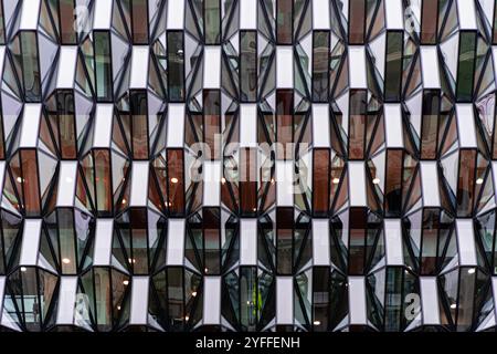 Modern Geometric Glass Facade of Urban High-Rise Building with Symmetrical Architectural Patterns and Reflections Stock Photo