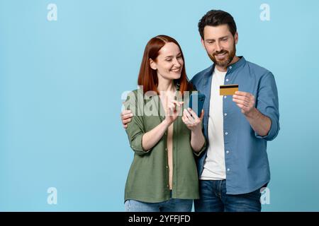 Cheerful couple is making an online purchase using a smartphone and a credit card, enjoying the convenience of e commerce Stock Photo