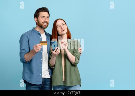 Couple is holding a credit card and a smartphone, looking up with excited expressions on their faces Stock Photo