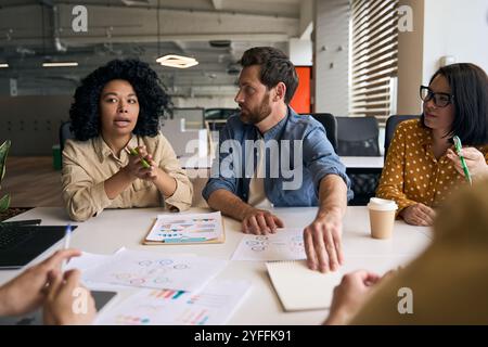 Young businesswoman is leading a meeting with her team, discussing new ideas for their next project Stock Photo