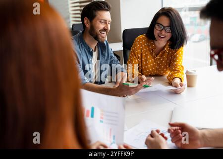 Team of business people are working together on a new project, using graphs and a laptop to help them analyze data Stock Photo