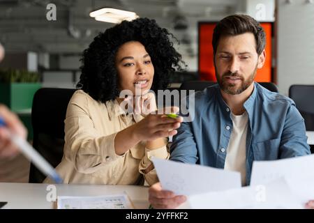 Two business partners are discussing over financial reports while working together at the office Stock Photo