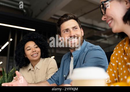 Diverse team in a busy office meeting, collaborating and brainstorming with laptops and coffee, exuding confidence and motivation Stock Photo