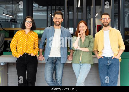 Four young professionals are posing in a modern startup company office environment Stock Photo
