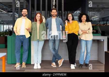 Five young creative professionals smiling while posing in their modern open plan office Stock Photo