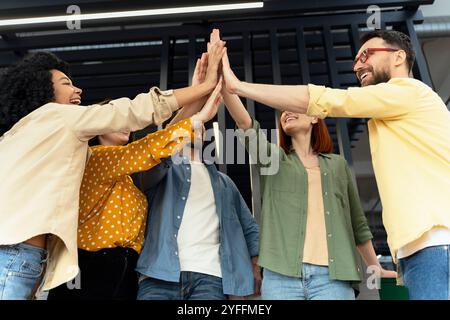 Team of diverse colleagues is celebrating success by giving a high five together in the office Stock Photo