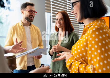 Group of businesspeople are standing in an office, smiling and discussing charts during a productive meeting Stock Photo