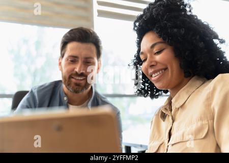 Two colleagues are smiling while reviewing notes on a clipboard during a meeting in the office Stock Photo