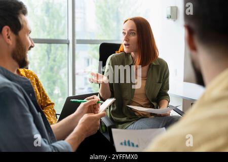 Young businesswoman is leading a brainstorming session, actively engaging in discussion and sharing her insights with her team Stock Photo