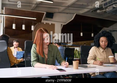 Young office workers are concentrating on their work while sitting at desks in a modern co working space Stock Photo