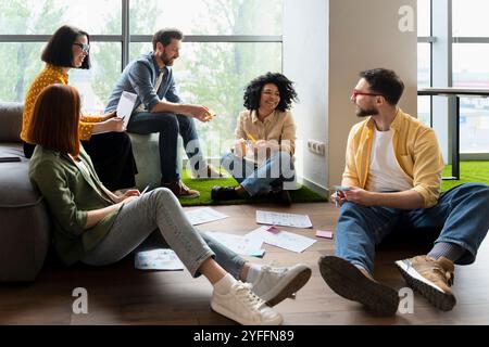 Coworkers are having a casual business meeting sitting on the floor and discussing new ideas Stock Photo
