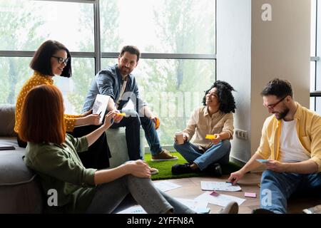 Diverse team of designers is having a productive brainstorming session, using sticky notes and digital tablets to develop innovative ideas Stock Photo