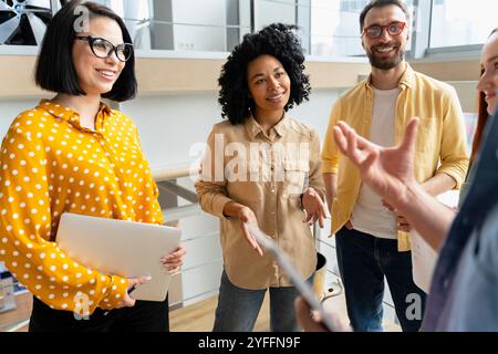 Diverse team of professionals is engaged in a lively discussion, sharing ideas and collaborating on a project in a modern office environment Stock Photo
