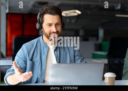 Businessman is having a video conference, smiling and gesturing while wearing a headset Stock Photo