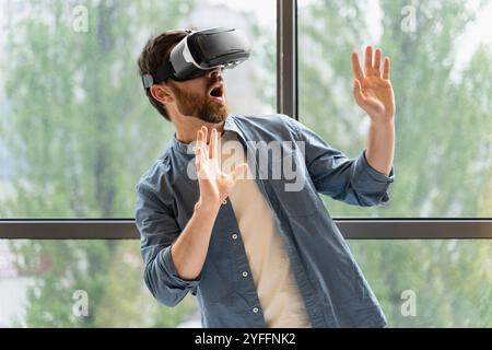 Young man is experiencing virtual reality using a vr headset and is excited by what he sees Stock Photo