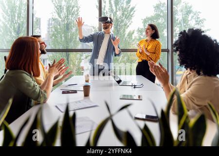 Team of coworkers are applauding a man using a vr headset during a business presentation in the office Stock Photo