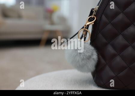 Stylish backpack with faux fur keychain on soft surface indoors, closeup. Space for text Stock Photo