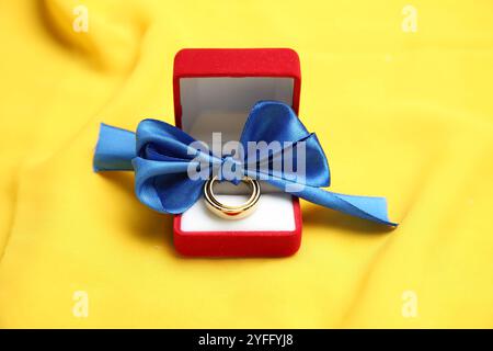 Wedding rings tied with ribbon in box on yellow cloth Stock Photo