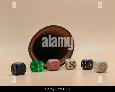 Shake and Roll the Dice – Leather Dice Cup with Colorful Dice on Light Brown Background Stock Photo