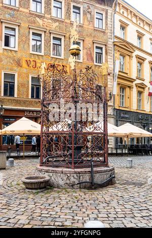 Water well in Male namesti, a triangular-shaped square with arcades surrounded by historical and colorful buildings, in Old Town, Prague, Czechia Stock Photo