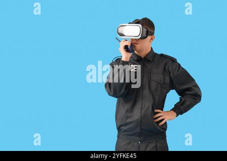 Male police officer in VR glasses with two-way radio on blue background Stock Photo