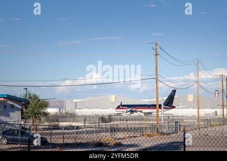 A black airplane parked on the tarmac of an American airport in front of maintenance hangars. The image highlights the aviation industry's operational Stock Photo