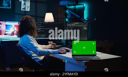 Admin using green screen laptop to implement security measures, protecting company systems and data. IT worker testing and debugging code for software applications on chroma key notebook, camera B Stock Photo