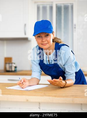 Woman house cleaner making notes in kitchen Stock Photo