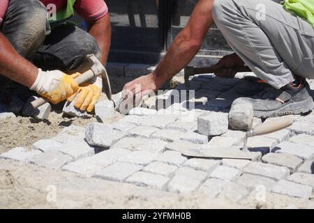 Group of Construction Workers Engaged in Laying Cobblestones on a Beautiful Pathway Stock Photo