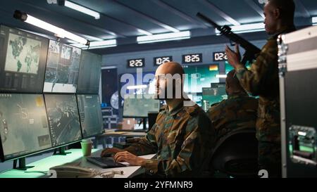 Military agent working in control room, analyzing aerial reconnaissance data. Intelligence corps agent controlling drones attacking strategic targets, camera B Stock Photo