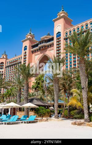 Exterior of 5 star luxury hotel, Atlantis the Palm hotel in Dubai with tropical palm trees and sunloungers on the beach, UAE,2024 Stock Photo