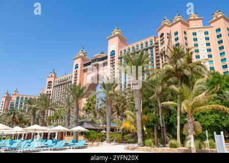 Luxury hotel resort in Dubai with building exterior,palm trees in the garden and sunloungers on the beach. Stock Photo