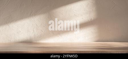 Soft light casting shadows on a textured wall and wooden surface in a serene indoor setting Stock Photo