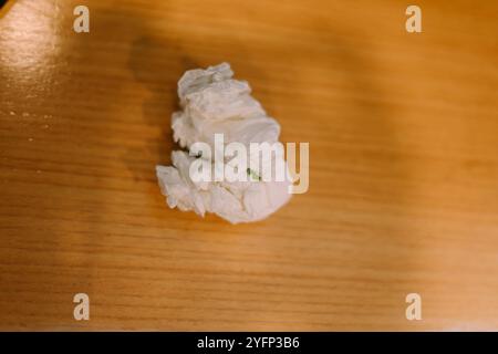 Used tissue paper discarded, crumpled and resting on a plain surface, showing everyday waste. Stock Photo