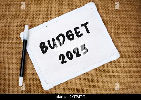 handwritten text "Budget 2025" on white chalkboard on burlap background Stock Photo