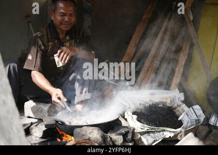 asian senior adult roasting coffee traditionally for sell at his shop Stock Photo