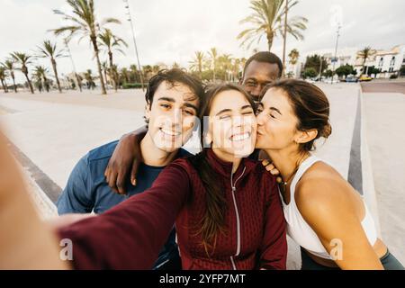 A diverse group of friends captures a happy selfie moment in a sunny outdoor setting after a workout session. Stock Photo