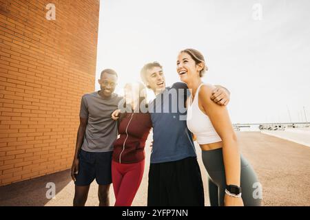 Cheerful group of friends enjoying a sunny day during an outdoor fitness session at the harbour. Stock Photo
