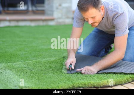 Man installing and cutting artifial turf in the garden at home Stock Photo